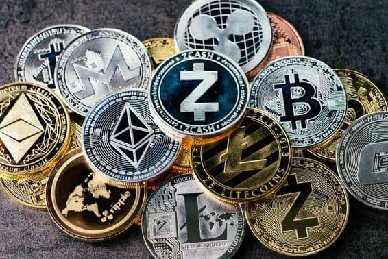 Símbolos de criptomoedas em moedas físicas brilhantes de prata e ouro.