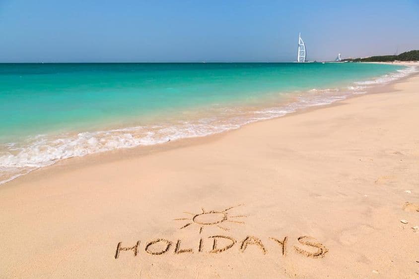 Placa de férias em uma praia com água turquesa.