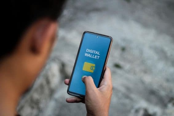 A mão de uma pessoa exibindo a tela de um smartphone mostrando a interface de aplicativos de carteira digital.