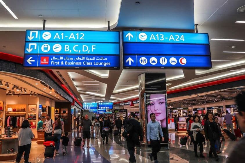 Passageiros caminhando em direção aos portões de embarque no Aeroporto Internacional de Dubai (DXB).