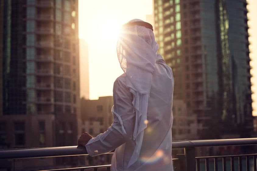 Homem árabe assistindo ao pôr do sol em Dubai.