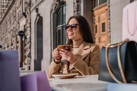 Uma garota usando óculos de sol bebendo café.