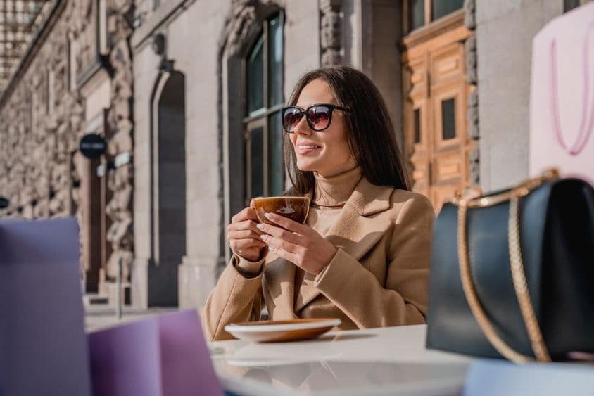 Uma garota usando óculos de sol bebendo café.