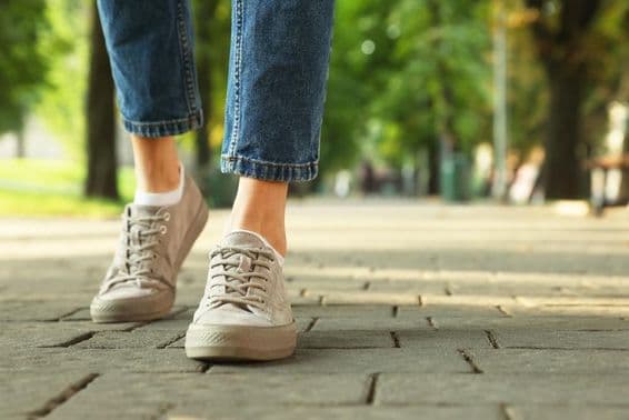 Mulher caminhando com tênis estiloso em rua da cidade.