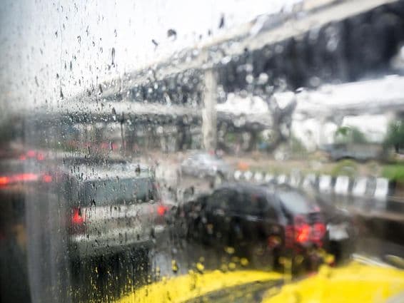 Trânsito em um dia chuvoso com gotas de chuva na janela do carro.