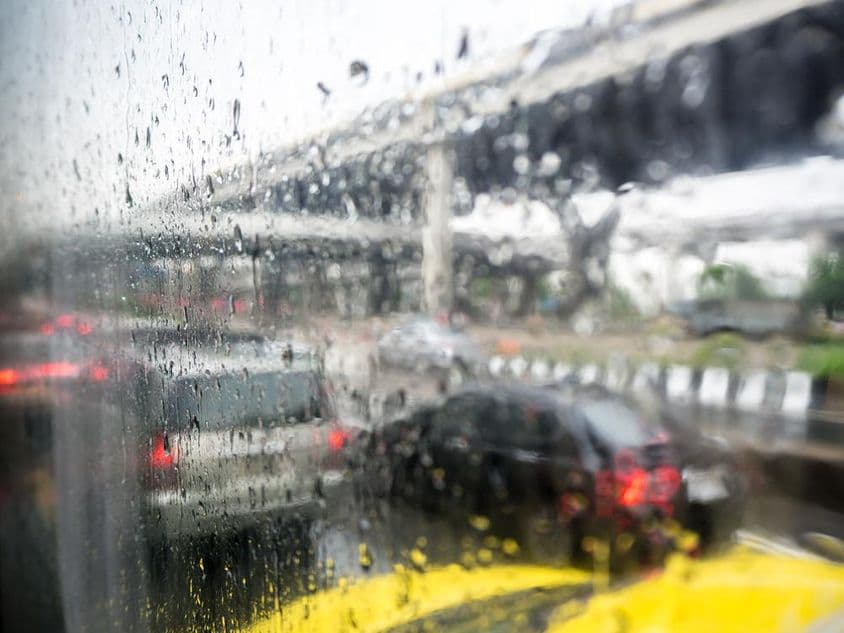 Trânsito em um dia chuvoso com gotas de chuva na janela do carro.