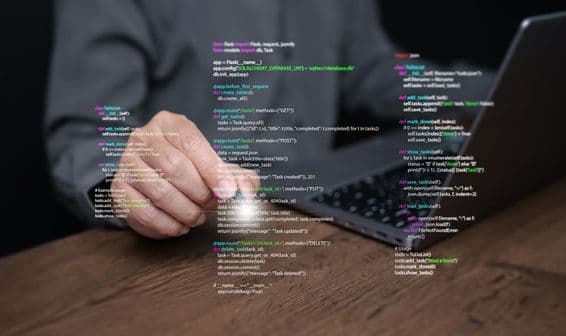 Mãos de um programador em um laptop com codificação.