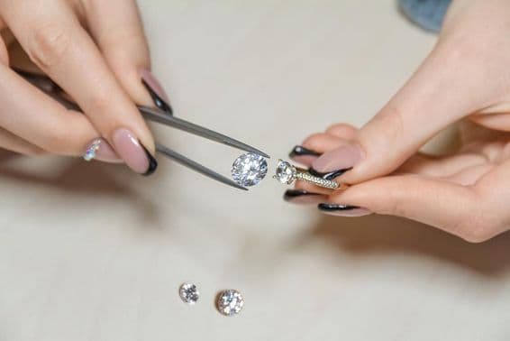 Mãos de uma joalheira segurando uma pedra preciosa.