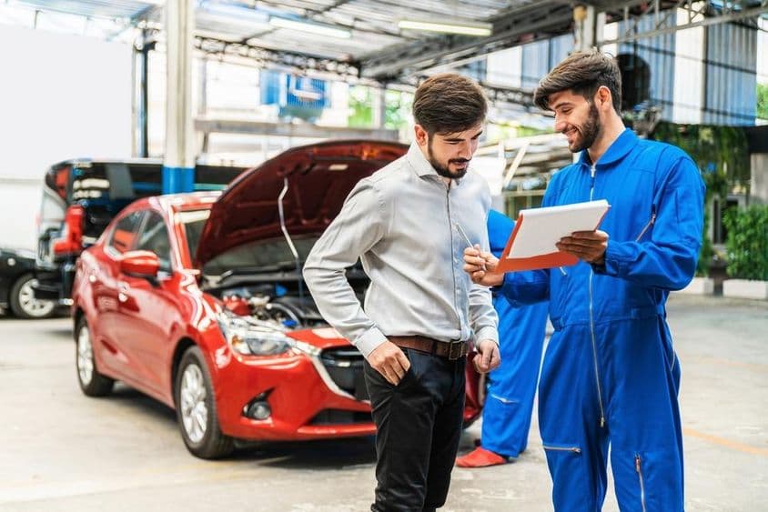 Mecânico mostrando lista de verificação de inspeção de carro para um cliente.