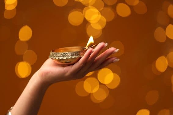 Mulher segurando uma lâmpada acesa de Diwali