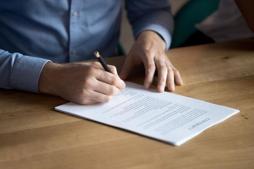 Empresário assinando um contrato manualmente.