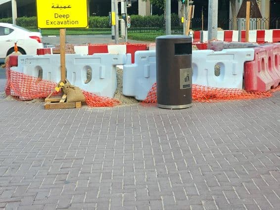 O reparo na estrada está cercado por barreiras plásticas e uma rede de segurança laranja.