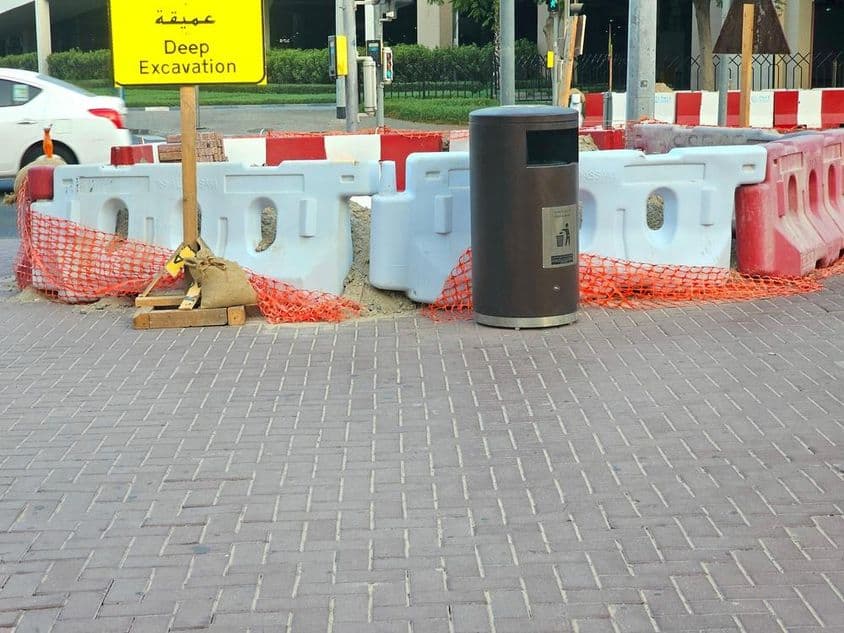 O reparo na estrada está cercado por barreiras plásticas e uma rede de segurança laranja.