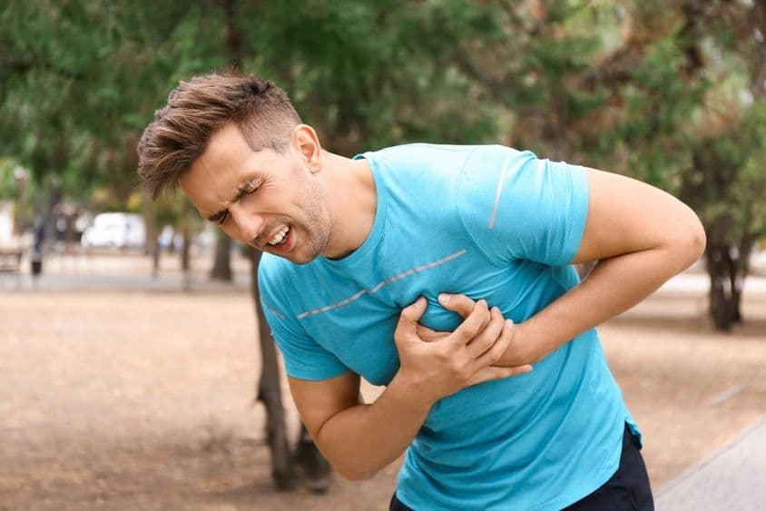 Jovem tendo um ataque cardíaco enquanto corre no parque.