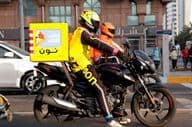 Entregador de moto entregando em rua de Dubai.