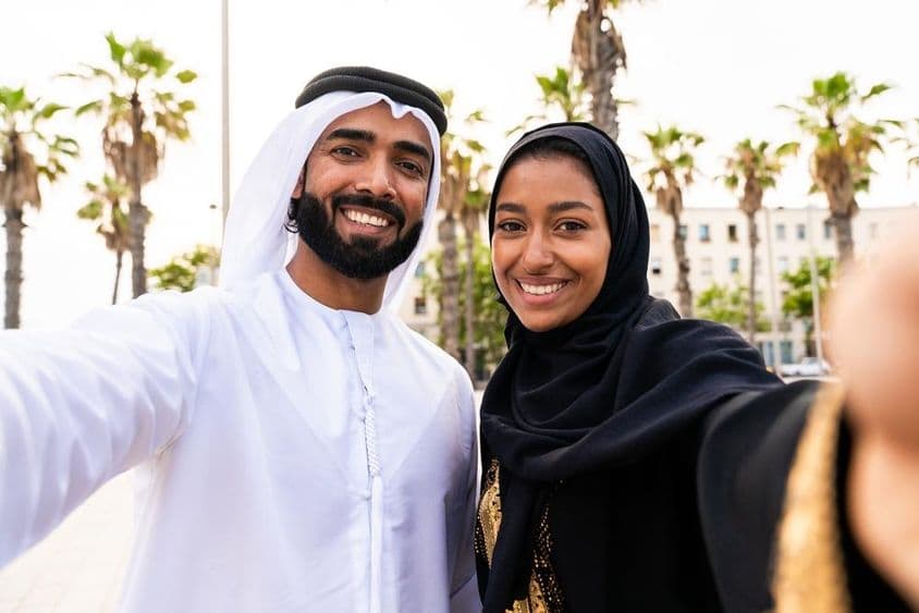 Casal tradicional árabe em trajes Emirati namorando ao ar livre.