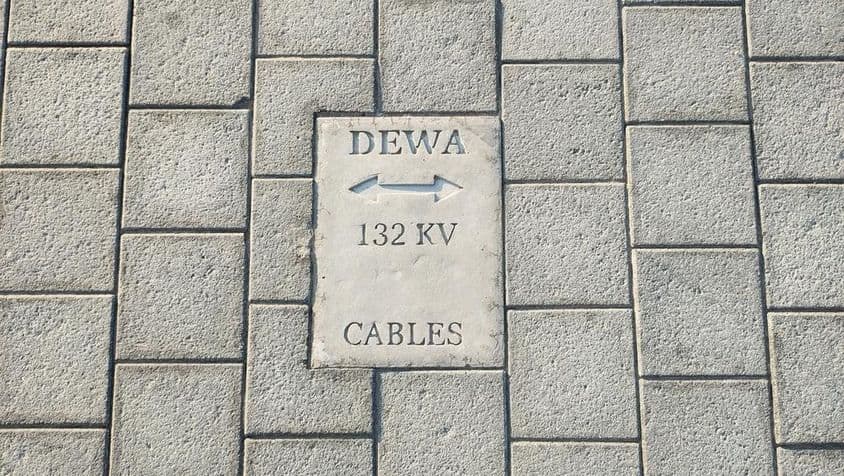 Sinal de aviso do escritório do governo da Autoridade de Eletricidade e Água de Dubai para cabos de 132 kV no chão.