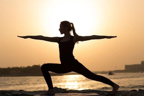 Uma mulher praticando ioga ao pôr do sol em Dubai.