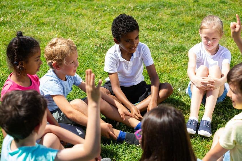 Crianças de escola primária conversando no gramado verde.
