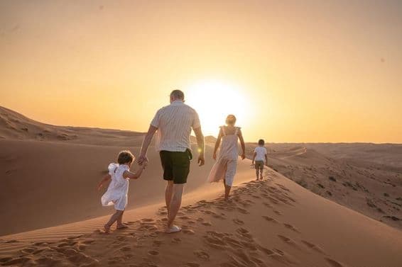 Uma família desfrutando do pôr do sol no deserto.
