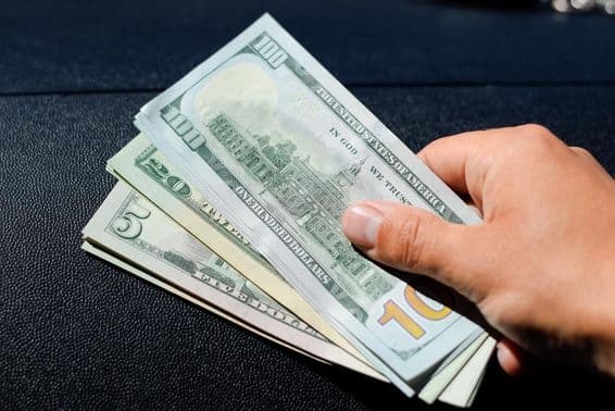 Um maço de dólares na mão de um homem.