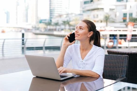 Mulher freelancer trabalhando em laptop sentada em um café ao ar livre.