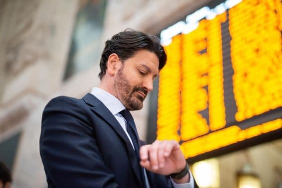 Um passageiro verifica a hora na frente de um horário.