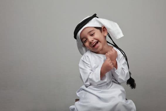 Menino jovem em traje árabe tradicional.