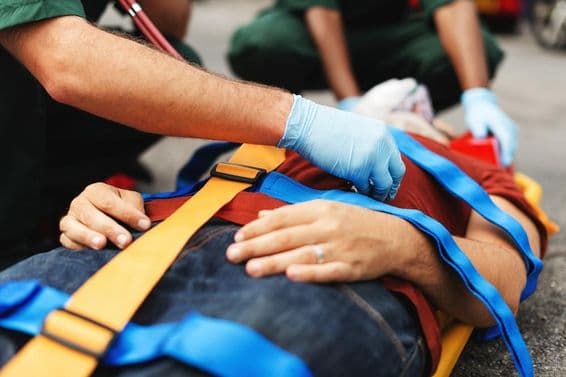 Pessoal de serviço de emergência auxilia um indivíduo ferido em uma maca.