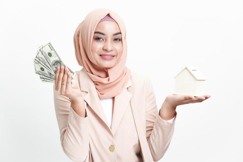Mulher de negócios muçulmana segurando dinheiro para compra de casa.