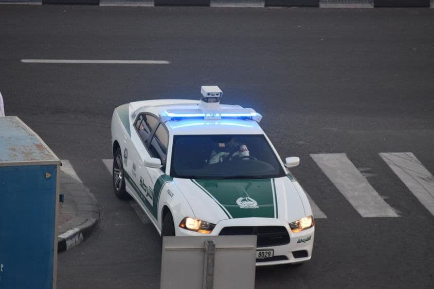 Um carro da polícia de Dubai dirigindo pela rua.