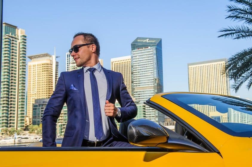 Empresário de sucesso em um conversível amarelo.