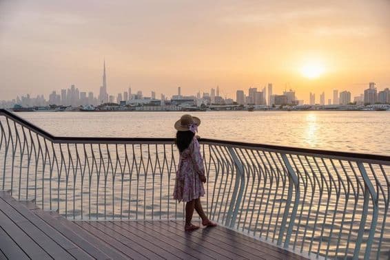 Jovem mulher olhando para o horizonte de Dubai ao pôr do sol.