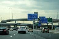 Estrada de Dubai com carro e propaganda em viaduto.