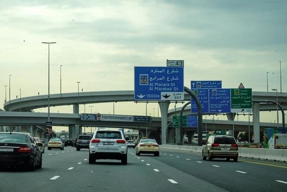 Estrada de Dubai com carro e propaganda em viaduto.