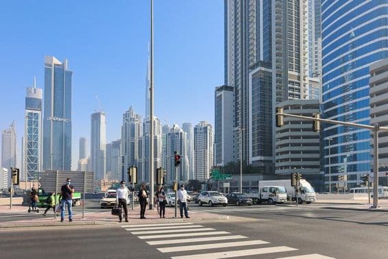 Pessoas caminhando em uma faixa de pedestres no distrito comercial de Dubai.