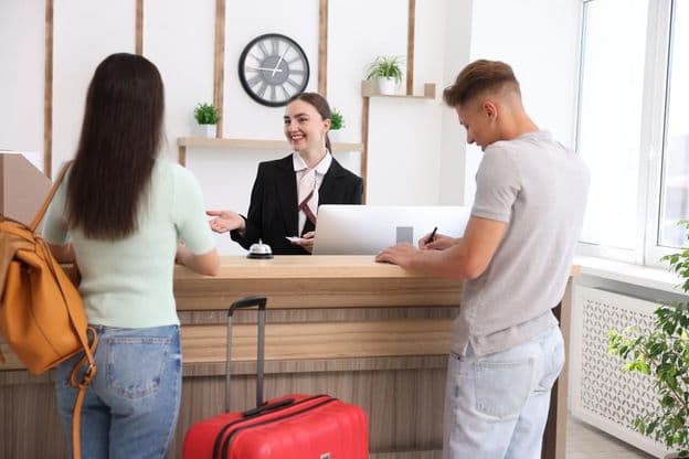 Recepcionista sorridente em uniforme com um cartão-chave de hotel.