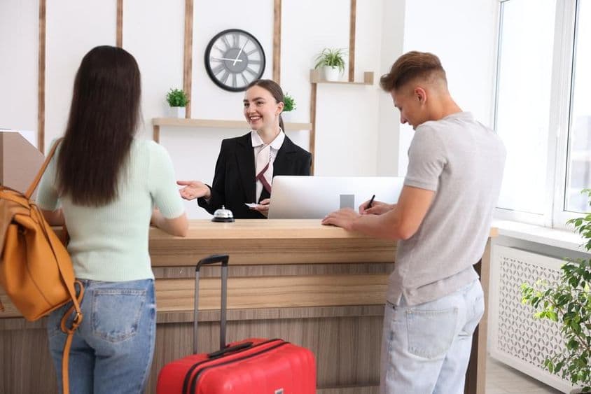 Recepcionista sorridente em uniforme com um cartão-chave de hotel.