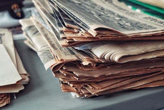 Jornais antigos empilhados com teias de aranha.