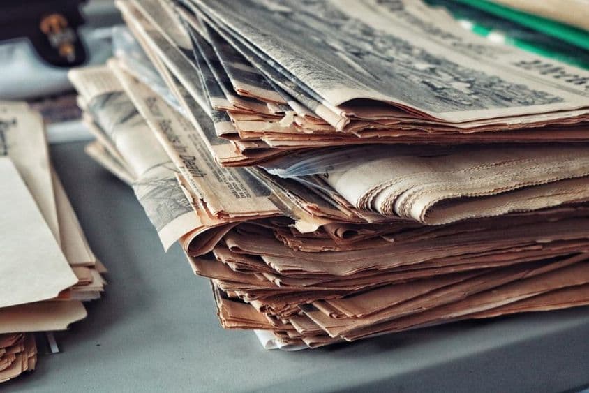 Jornais antigos empilhados com teias de aranha.