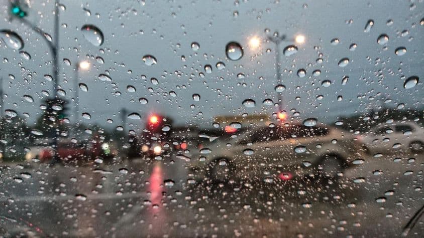 Gotas de água borradas no fundo, vistas de uma janela de carro em um dia chuvoso em Dubai.
