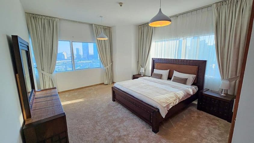 Quarto em apartamento mobiliado com cama king-size e janelas.
