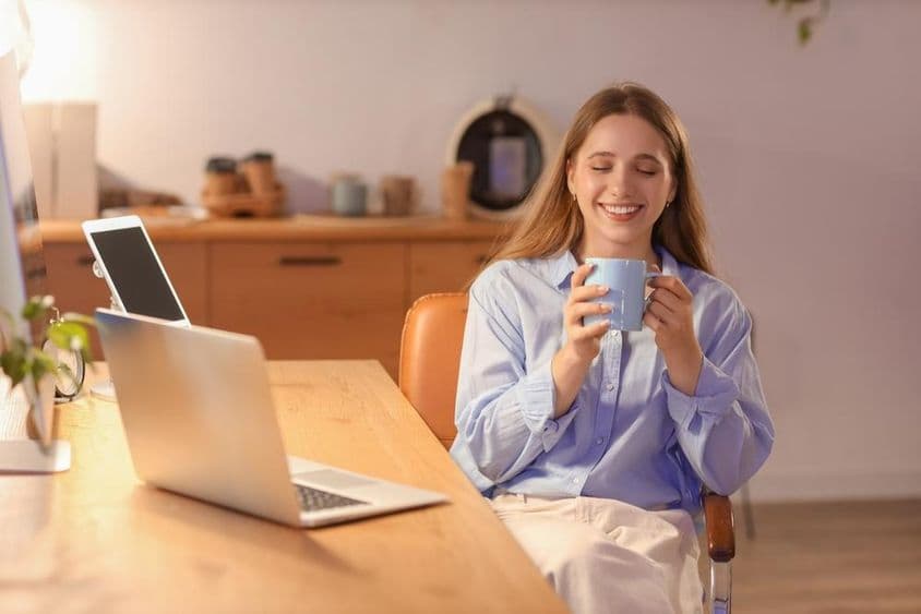 Jovem empresária bebendo café no escritório à noite.