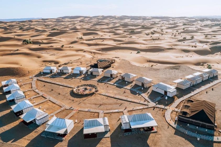 Acampamento no deserto cercado por vastas dunas de areia.