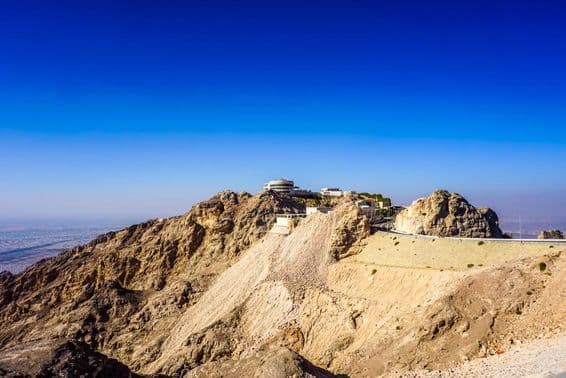 Paisagem da montanha Jebel Hafeet em Al Ain com picos e prédios.