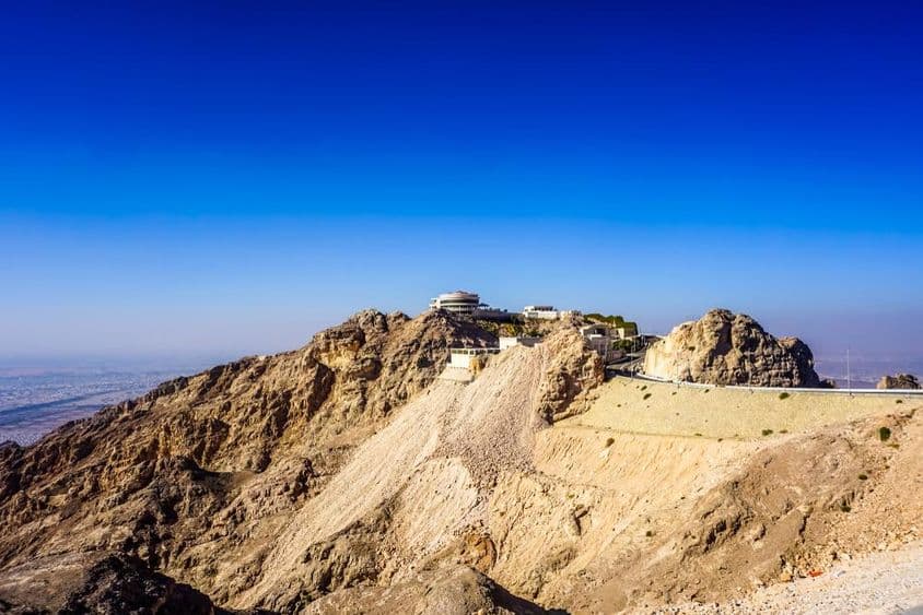 Paisagem da montanha Jebel Hafeet em Al Ain com picos e prédios.