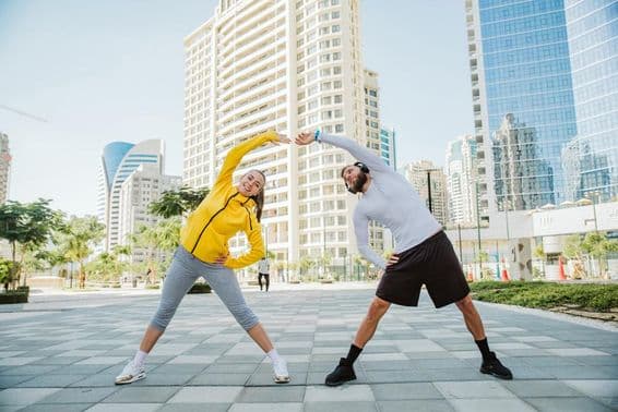 Um homem e uma mulher alongando-se juntos após um treino em Dubai.