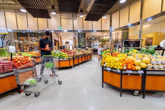 Entregador selecionando legumes e frutas em um supermercado.