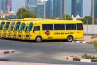 Linha de ônibus escolares amarelos de Dubai estacionados do lado de fora.