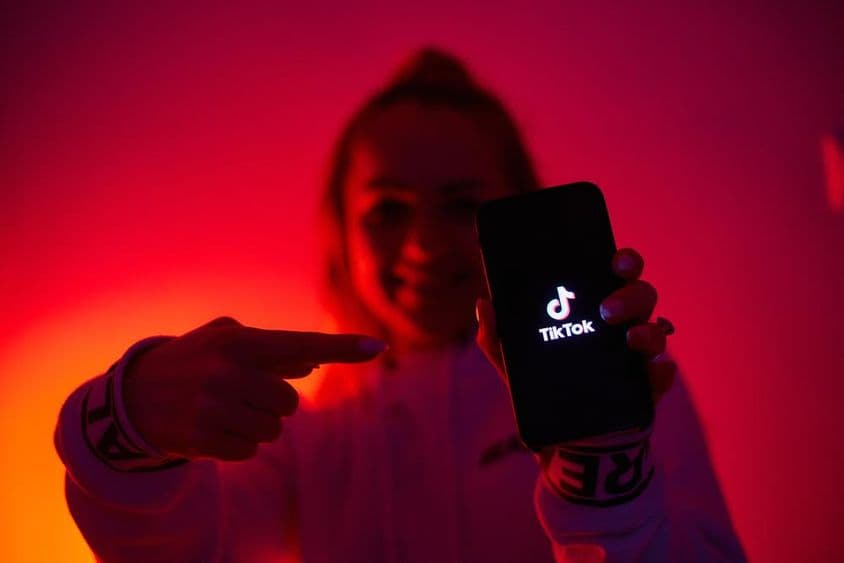 Uma garota com um lado sombrio, segurando um smartphone, promovendo redes sociais.